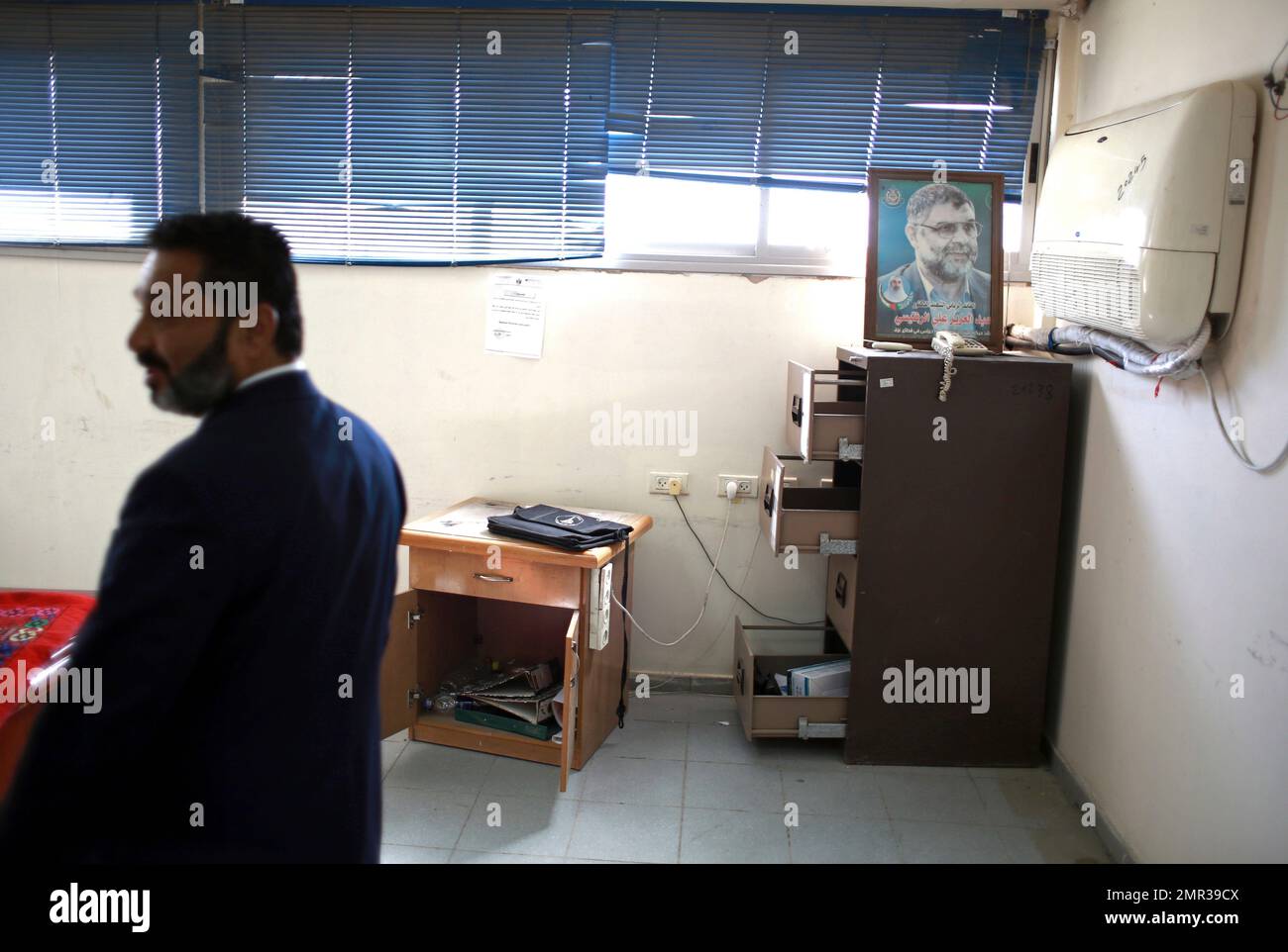A Palestinian security officer checks an office with a poster of the ...