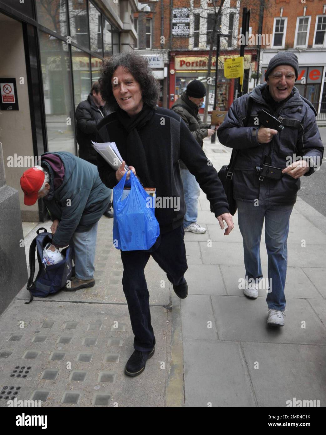 EXCLUSIVE!! 1970's pop icon and Irish singer songwriter Gilbert O'Sullivan  smiles and carries a bag of Jersey Cream Toffee candies, a gift for BBC  radio host Steve Wright, as he arrives at