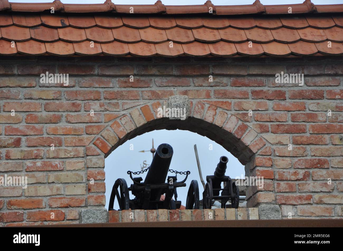 German-style villa in Obernberg am Inn, Germany December 2022.miniature replicas of cannons as decoration on the window of the brick wall. Stock Photo