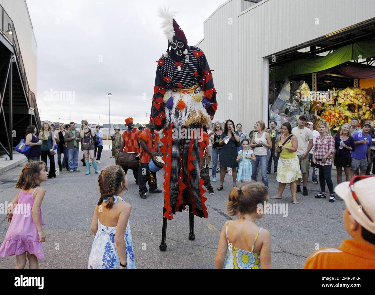 A costumed figure on stilts walks in front of children during the