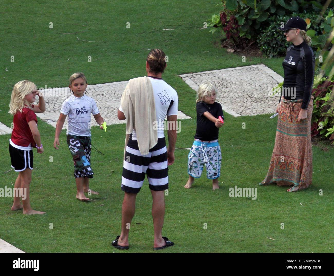 EXCLUSIVE!! Gwen Stefani, husband Gavin Rossdale and the couple's two children Kingston and Zuma spend a fun afternoon playing American Football on the lawn of their luxury hotel. Gavin tried to show Gwen how to throw the ball properly while the boys were more interested in playing in the fountain and filling up their water pistols. Gwen stayed covered up in a surfer's top, baseball cap and sarong and stayed in the shade as much as possible. She was also spotted texting and checking her messages on her iPhone while Gavin played with the kids. The family are spending time together ahead of Gavi Stock Photo