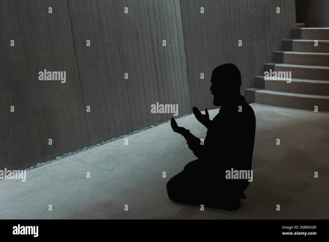 Silhouette of a muslim man praying in the mosque with raising hands ...