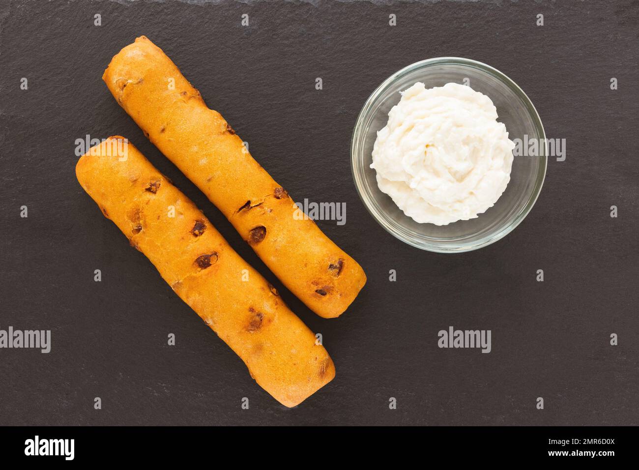 Two chorizo breadsticks and garlic cheese dipping sauce in bowl on