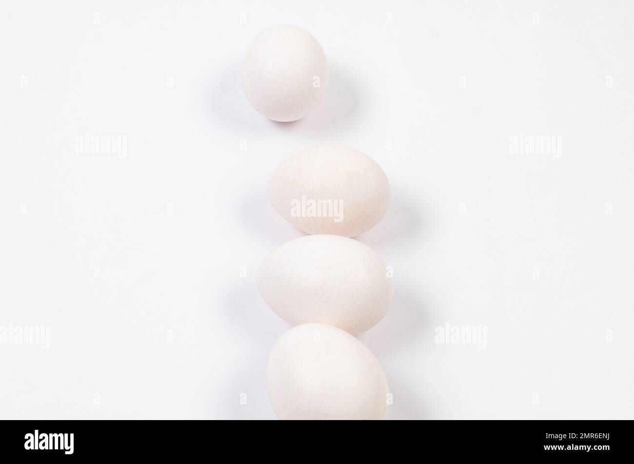 Fresh white chicken eggs close-up on white background. Group of four eggs. Stock Photo