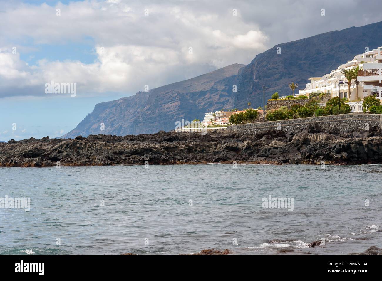 Rocky coast of Tenerife island with famous Los Gigantes cliffs in the background. Canary Islands, Spain Stock Photo