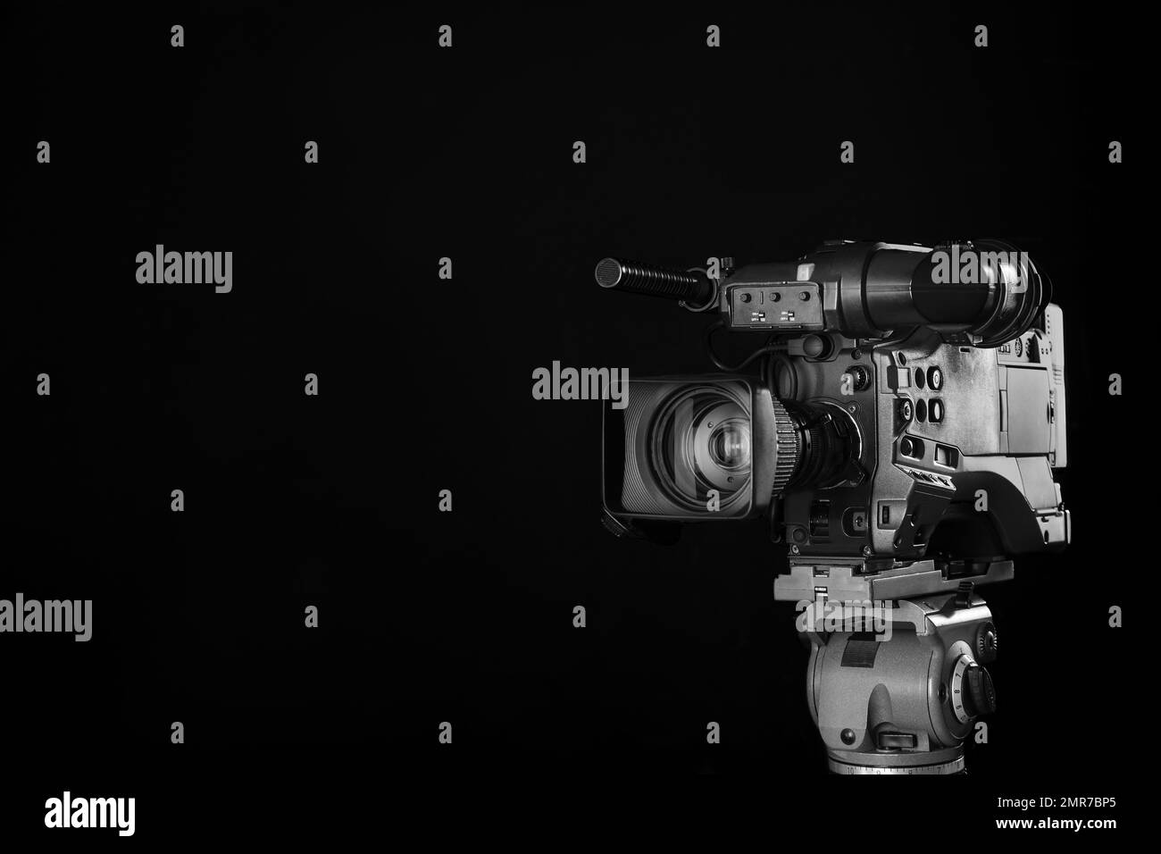 Modern professional video camera on black background. Space for text