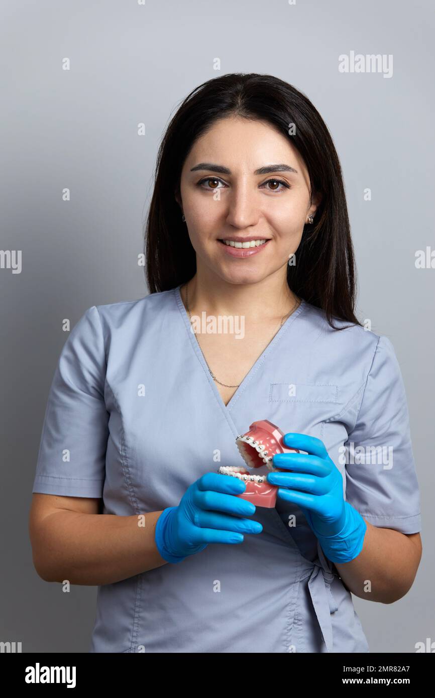 Doctor orthodontist showing model of human jaw with wire braces