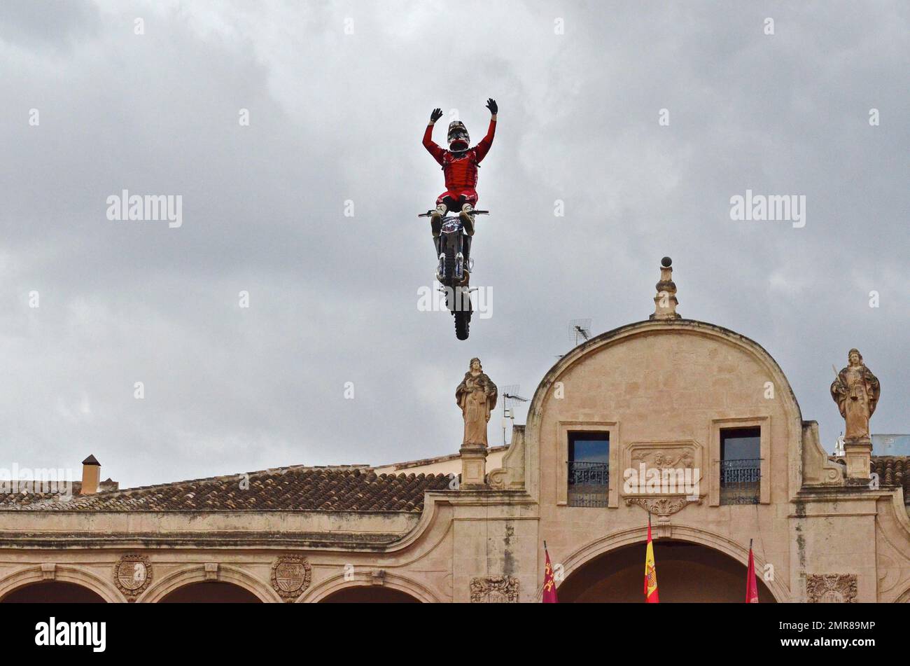 Motorbike performer flies through the air with arms raised above the ...