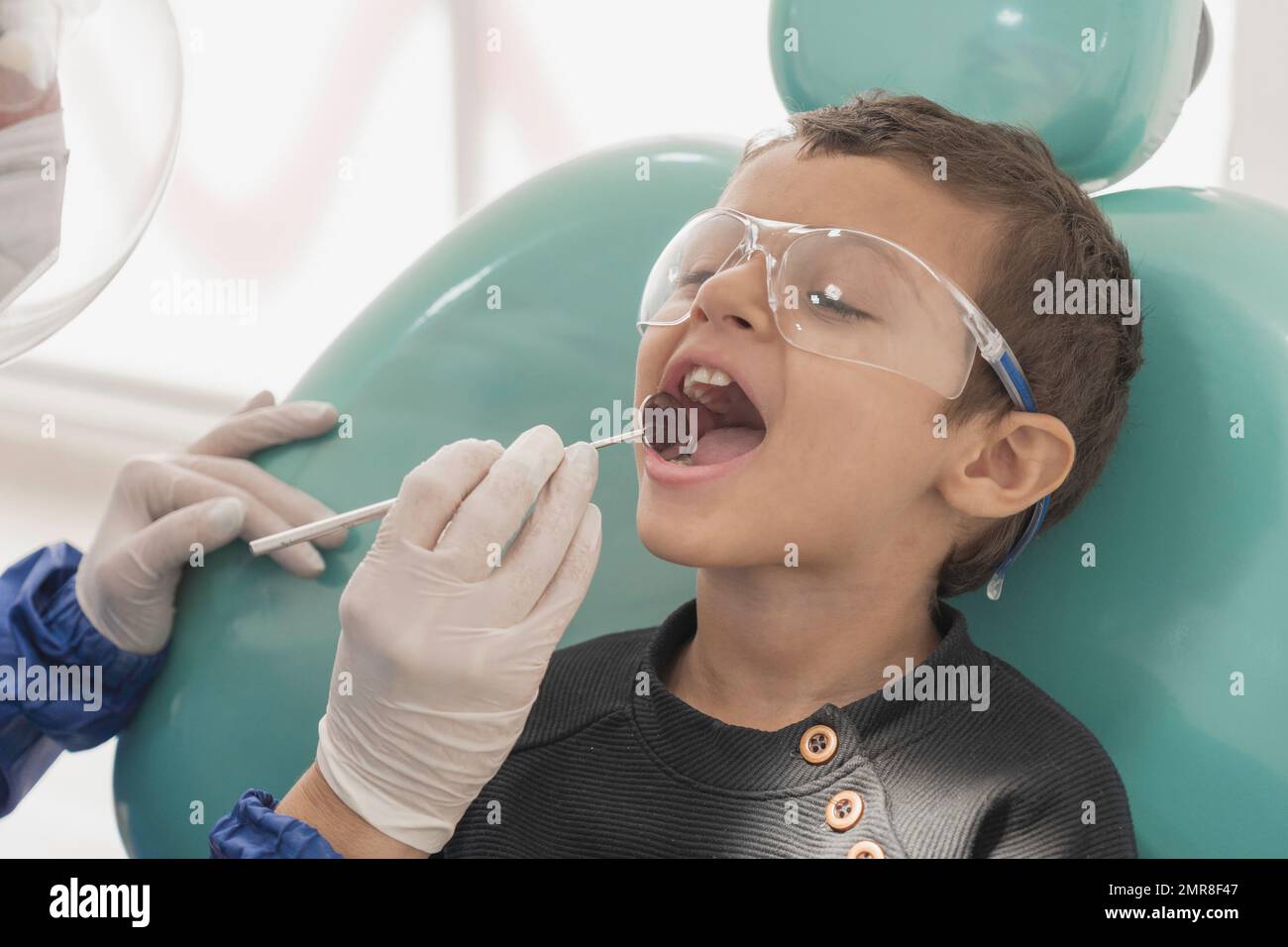 A toddler boy getting his teeth checked by a dentist in a the dental
