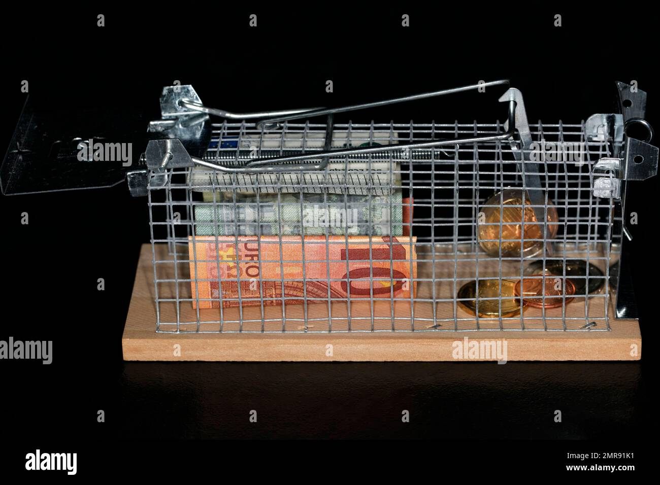 Euro coins and paper money lying in a live trap for mice symbol photo