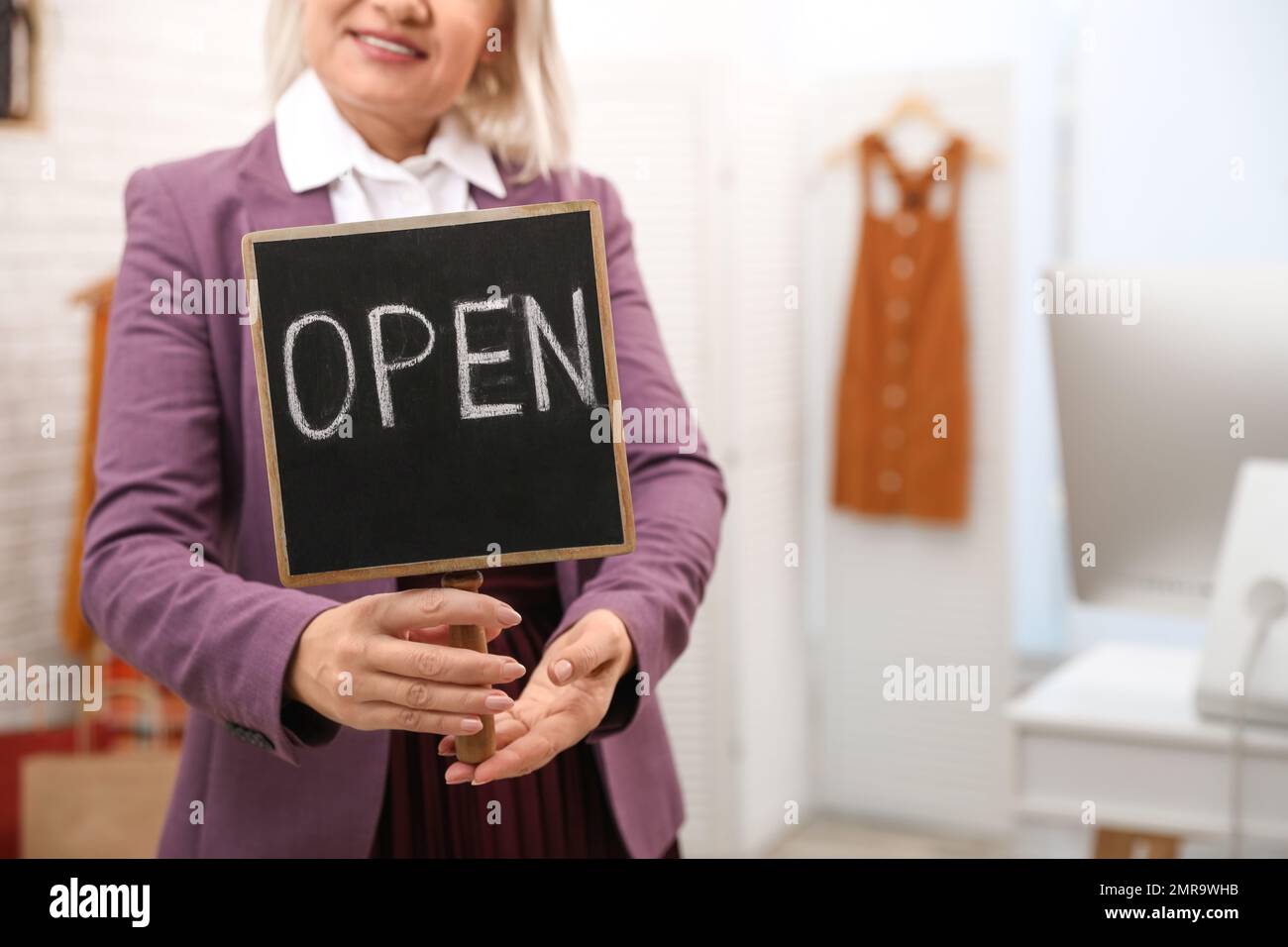 Female business owner holding OPEN sign in boutique, closeup Stock Photo