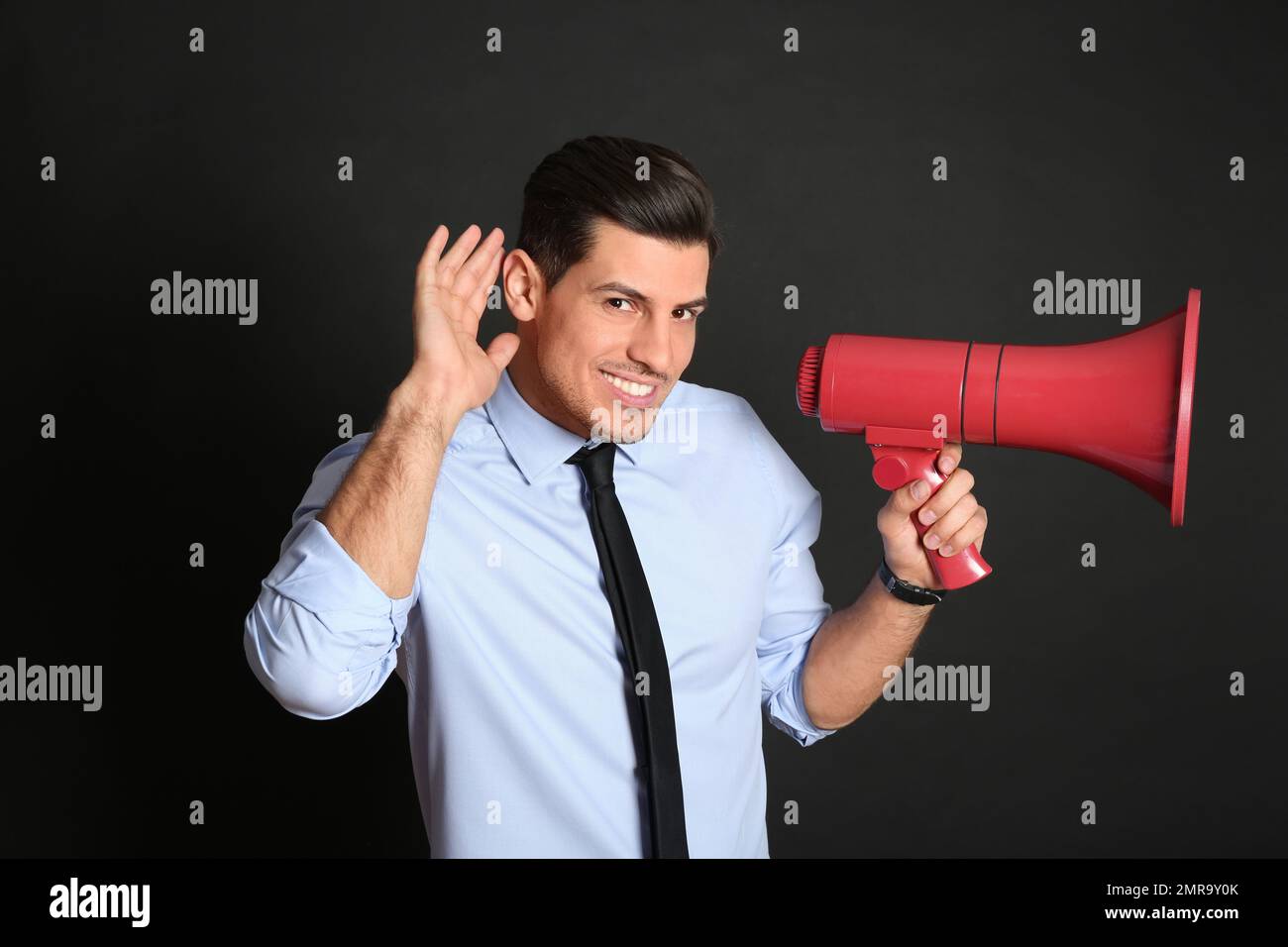 Handsome man with megaphone on black background Stock Photo