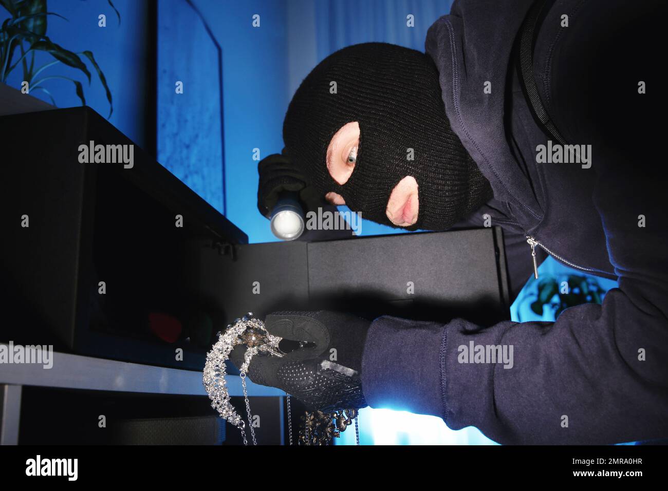 Thief taking jewelry out of steel safe indoors at night Stock Photo Alamy