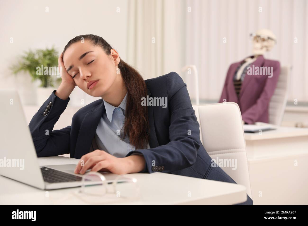 Young woman sleeping at table and human skeleton on background Stock Photo
