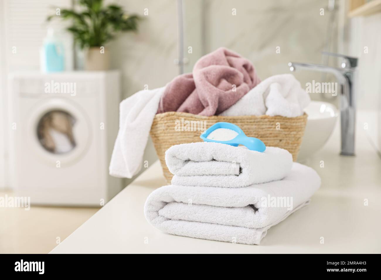 Clean towels and detergent powder on countertop in bathroom Stock Photo -  Alamy