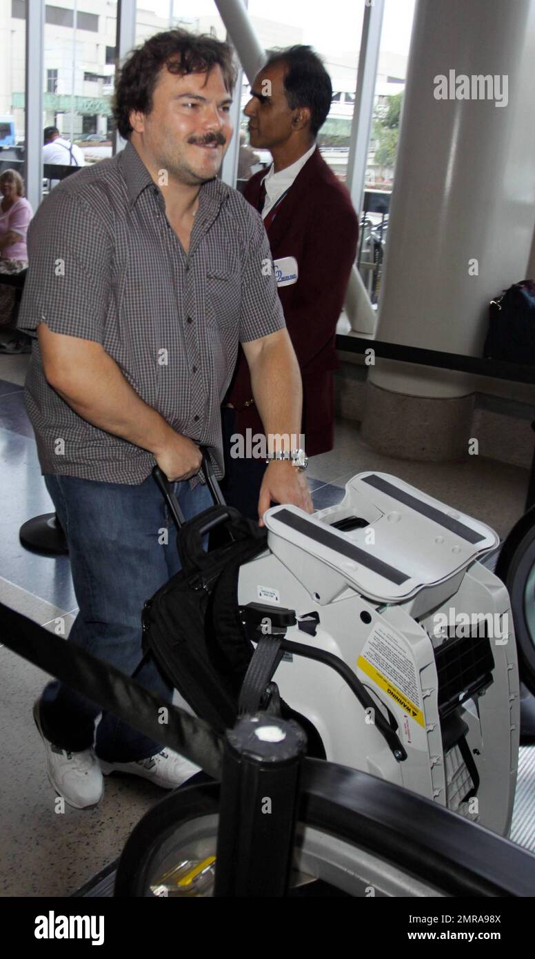 EXCLUSIVE!! Actor and funnyman Jack Black carries along an infant's car seat as he arrives for a flight at LAX. Black, who made faces for photographers as he ascended an elevator, is set to star alongside Matthew McConaughey, Shirley MacLaine and Rip Torn in the new black comedy 'Bernie.' The movie is based on a true story and tells the tale of a small-town funeral home director in Texas. Los Angeles, CA. 10/3/10. Stock Photo