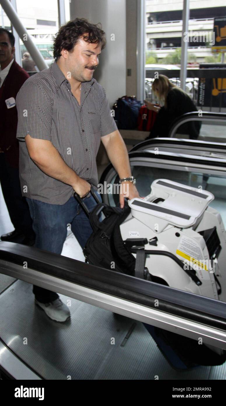 EXCLUSIVE!! Actor and funnyman Jack Black carries along an infant's car seat as he arrives for a flight at LAX. Black, who made faces for photographers as he ascended an elevator, is set to star alongside Matthew McConaughey, Shirley MacLaine and Rip Torn in the new black comedy 'Bernie.' The movie is based on a true story and tells the tale of a small-town funeral home director in Texas. Los Angeles, CA. 10/3/10. Stock Photo