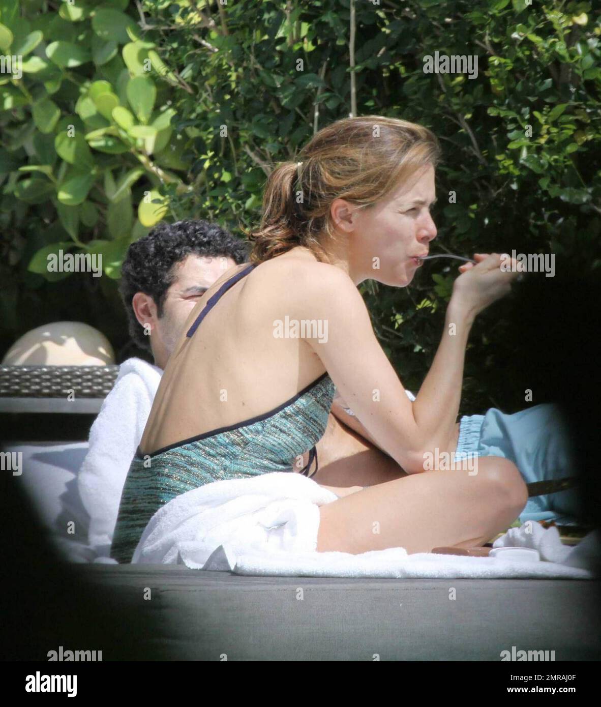 French actor Jamel Debbouze and wife Melissa Theuriau enjoy a day in the sun wearing bathing suits at their exclusive Miami Beach hotel pool.  The couple had lunch and were very intimate together, kissing and cuddling in front of hotel guests. Miami Beach, Florida. 2/23/09 Stock Photo