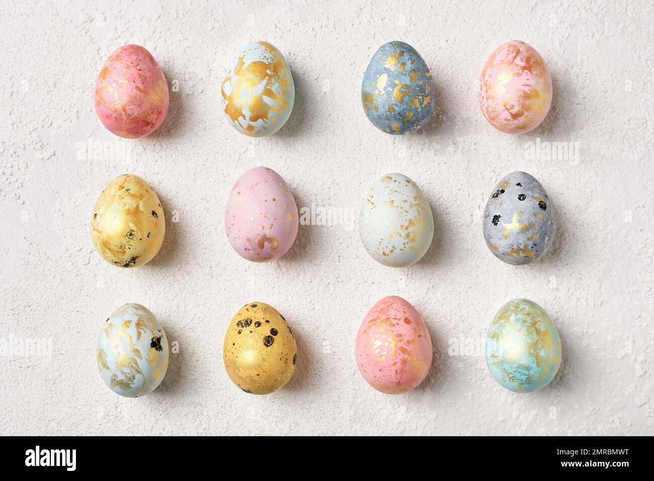 Decorated multicolor pastel Easter eggs with gold on white table. Flat lay geometric pattern. Happy Easter card. Stock Photo