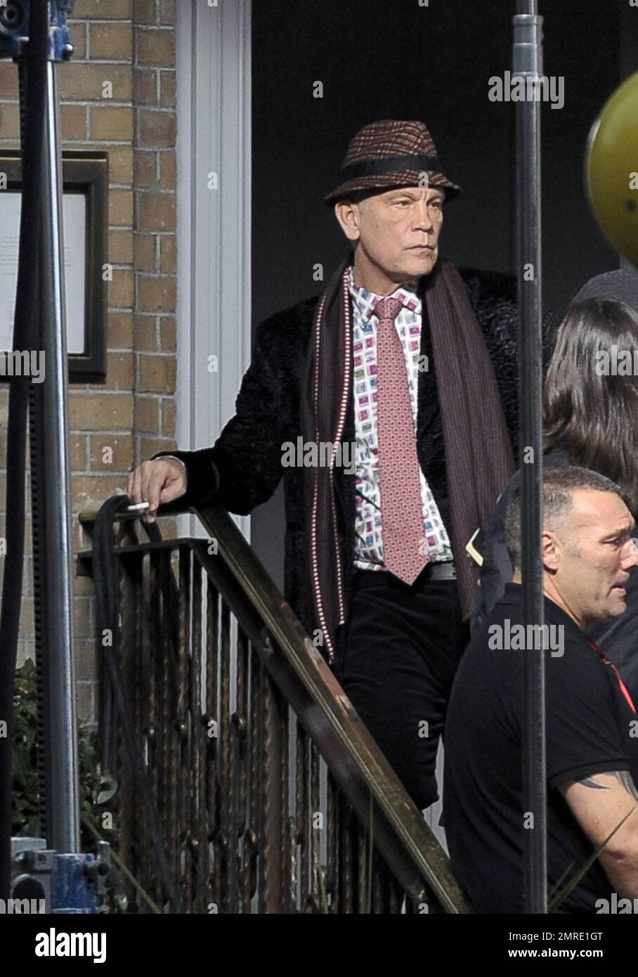 Actor John Malkovich smokes a cigarette while on the set of 