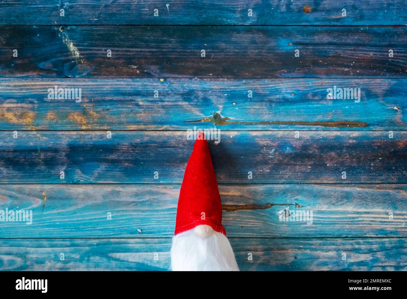 A top view of a cute red Christmas gnome toy on a blue wooden surface with copy space Stock Photo