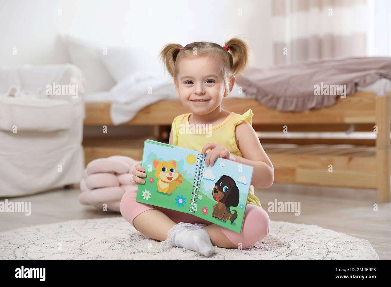 Cute little girl with book at home Stock Photo - Alamy