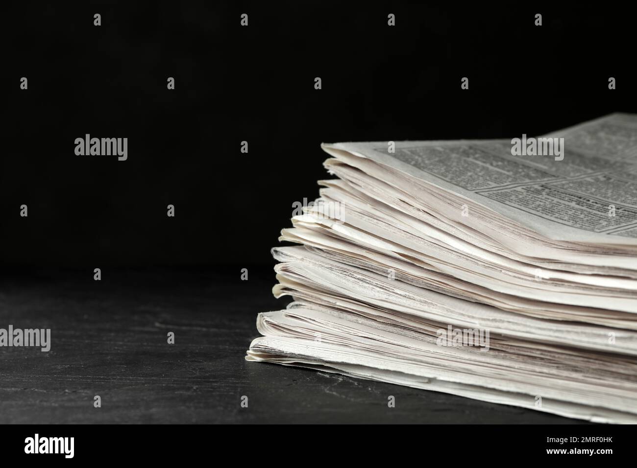 Stack of newspapers on dark stone table, space for text. Journalist's work Stock Photo