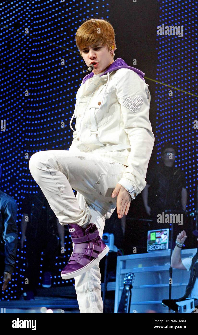 In a white buckle-detailed jacket, trendy paint splattered white jeans and his trademark purple high top sneakers teen heartthrob Justin Bieber performs live in concert at the American Arena. Bieber threw