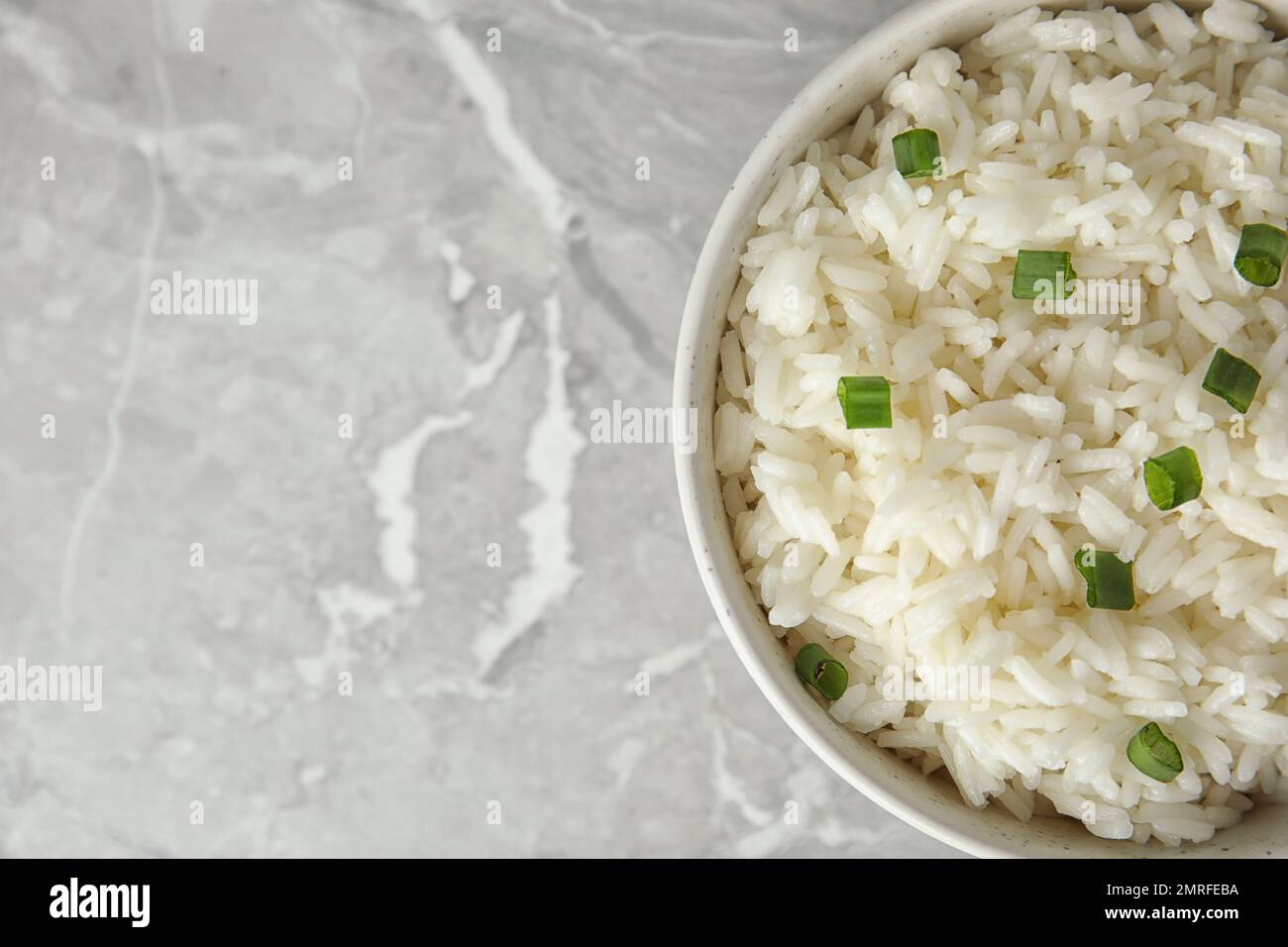 Bowl with tasty cooked rice on light grey marble table, top view. Space ...