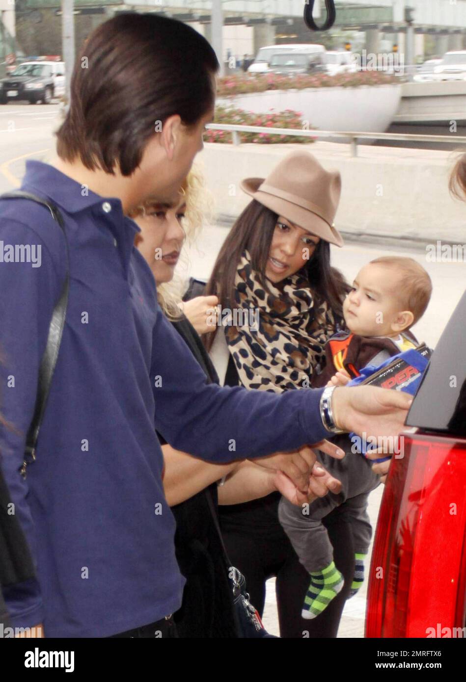 EXCLUSIVE!! Reality TV stars and fashionista sisters Kim and Kourtney Kardashian got dolled up for their trip to the airport with Kim's beau Scott Disick, their baby son Mason, the nanny and their well-dressed friends all headed to New York where they're reportedly working on a new spin off show.  The family piled out on to the sidewalk after arriving at LAX, moving their many designer Coach and Louis Vuitton suitcases around and fawning over little Mason.  And so sister Kourtney could sort out her own luggage Kim took hold of Mason and carried him inside.  Los Angeles, CA. 10/03/10. Stock Photo