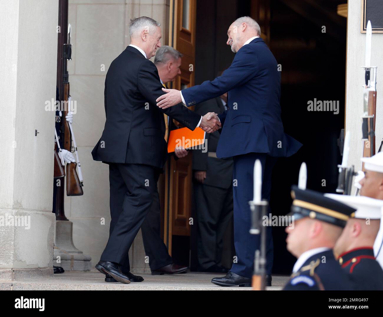 Defense Secretary Jim Mattis, left, shakes hands with Polish Defense 