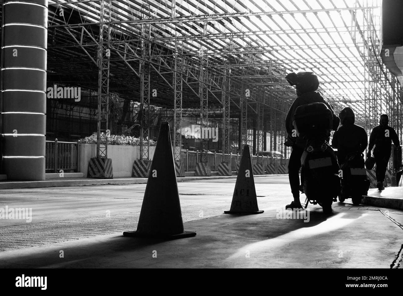 Silhouette of Motorcycle Delivery Riders Waiting Under a Scaffolding ...