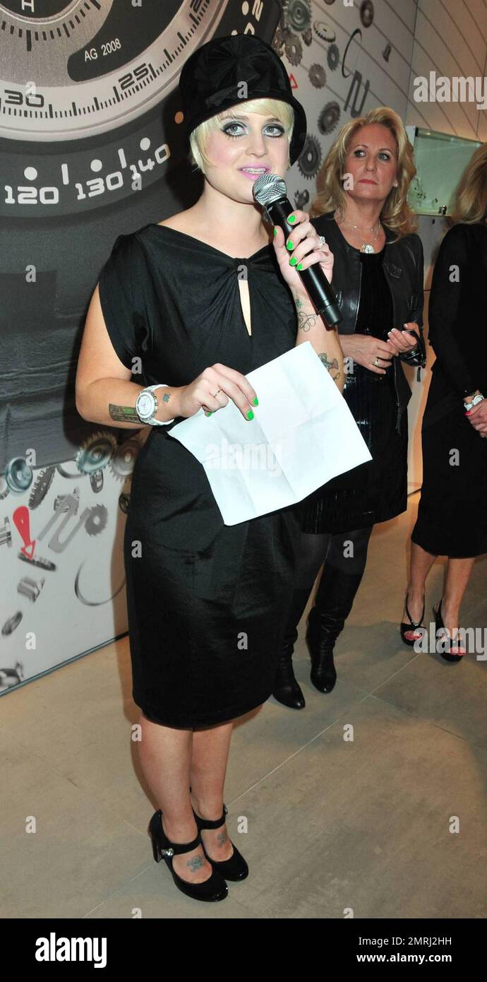 Kelly Osbourne totes along her little black dog, which matches her outfit  perfectly, as she attends the grand re-opening of NYC's Swatch store. Kelly  wears a simple black dress and hat paired