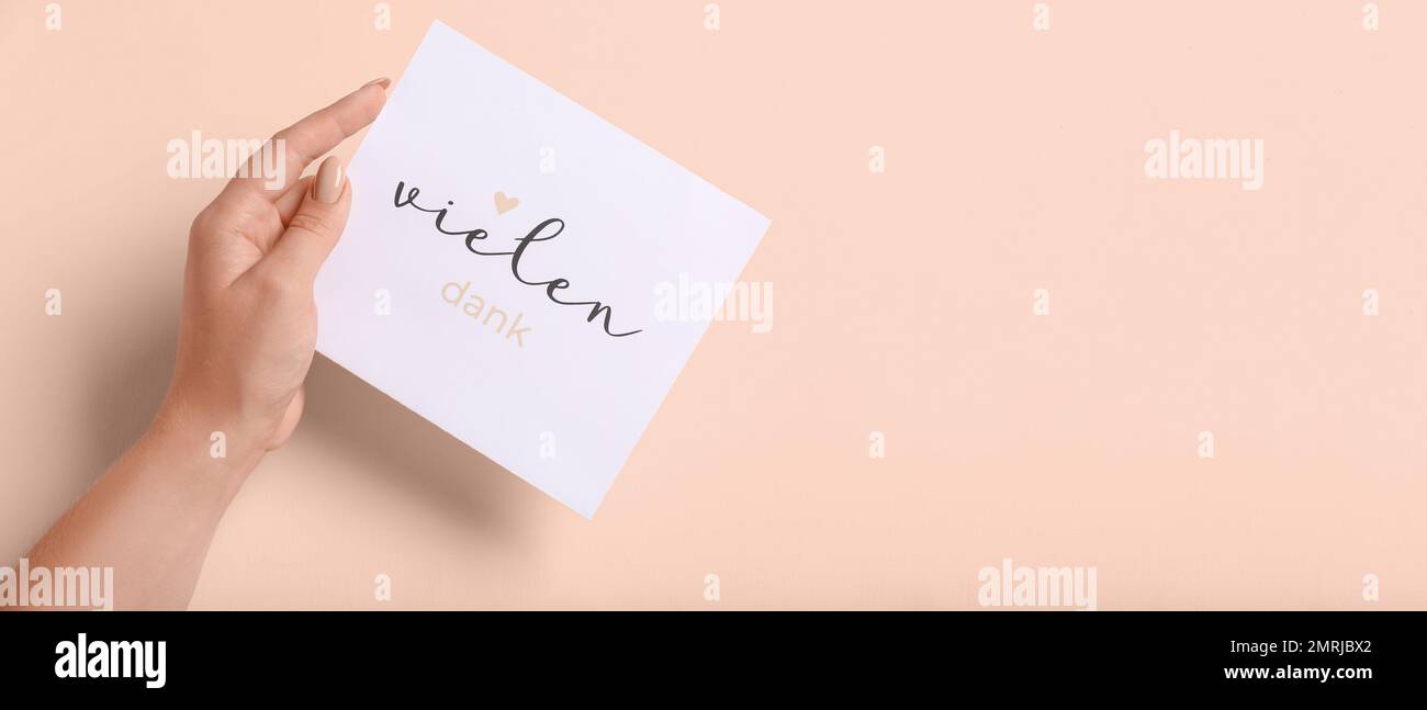 Female hand holding card with text VIELEN DANK on pink background with space for text Stock Photo