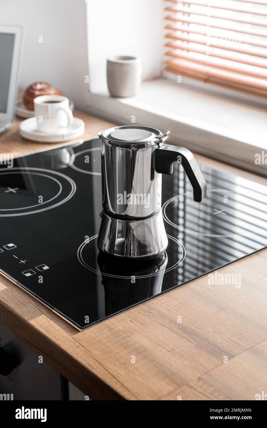 Geyser coffee maker on electric stove in kitchen near window Stock