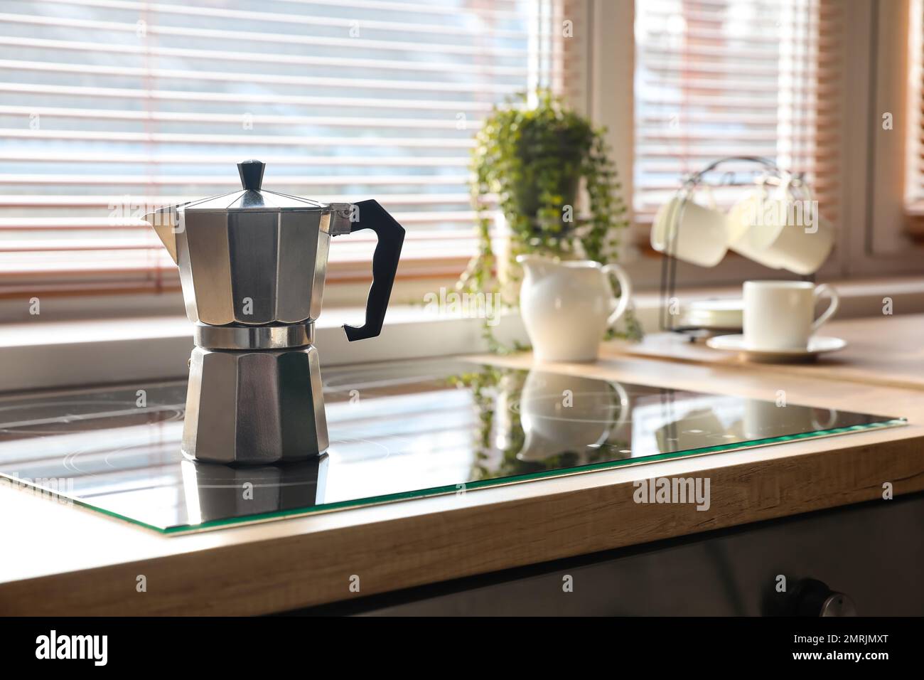 Geyser coffee maker on electric stove in kitchen near window Stock