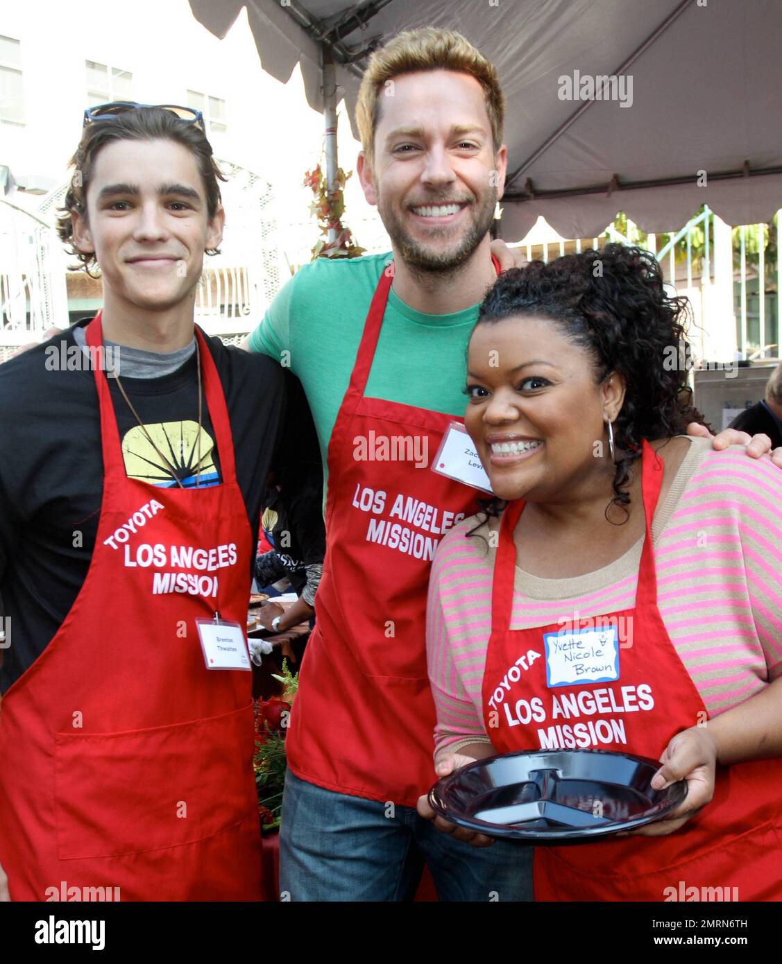 L R Brenton Thwaites Zachary Levi and Yvette Nicole Brown serve food at the LA Mission Thanksgiving meal. Los Angeles CA. 21st November 2012 Stock Photo Alamy