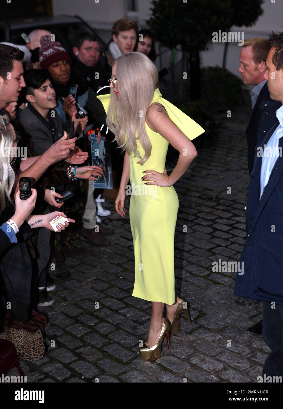 Wearing a lime green dress gold high heels and heart shaped sunglasses pop superstar Lady Gaga greets fans as she leaves her luxury hotel in London UK. 15th November 2011 Stock Photo