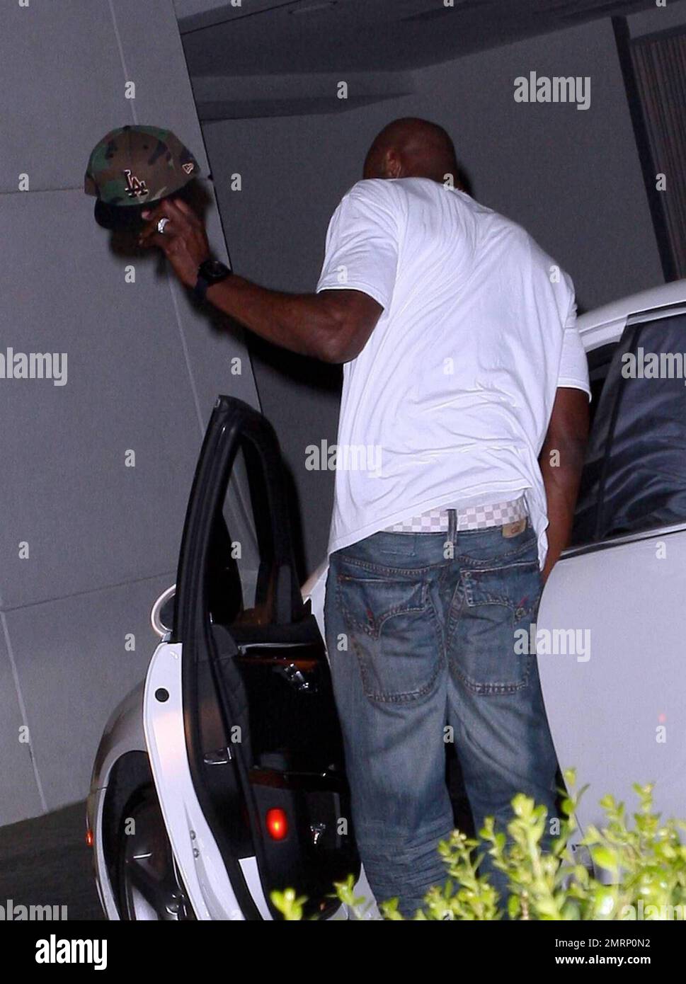 EXCLUSIVE!! Khloe Kardashian's new husband, LA Lakers player Lamar Odom, is alone as he leaves the hotel where the couple spent their first night together as husband and wife earlier this week. Odom, carrying a bottle of perfume or cologne and wearing jeans, a t shirt and sneakers, waves his hat as he gets in his car to leave. Los Angeles, CA. 10/2/09. Stock Photo