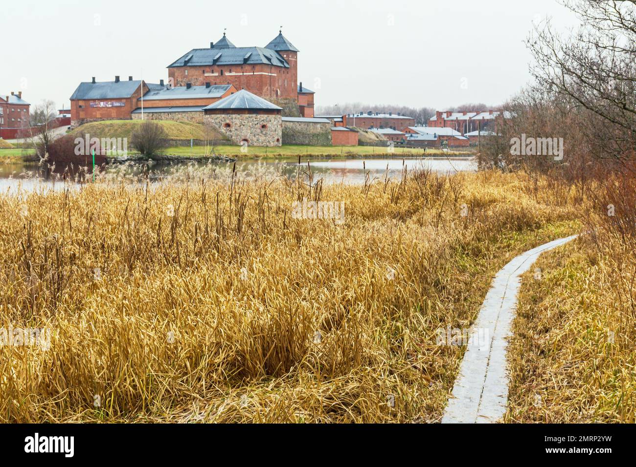 Old frosty boardwalk among the reeds by Vanajavesi lake with medieval Häme Castle in background  in Hämeenlinna Finland Stock Photo