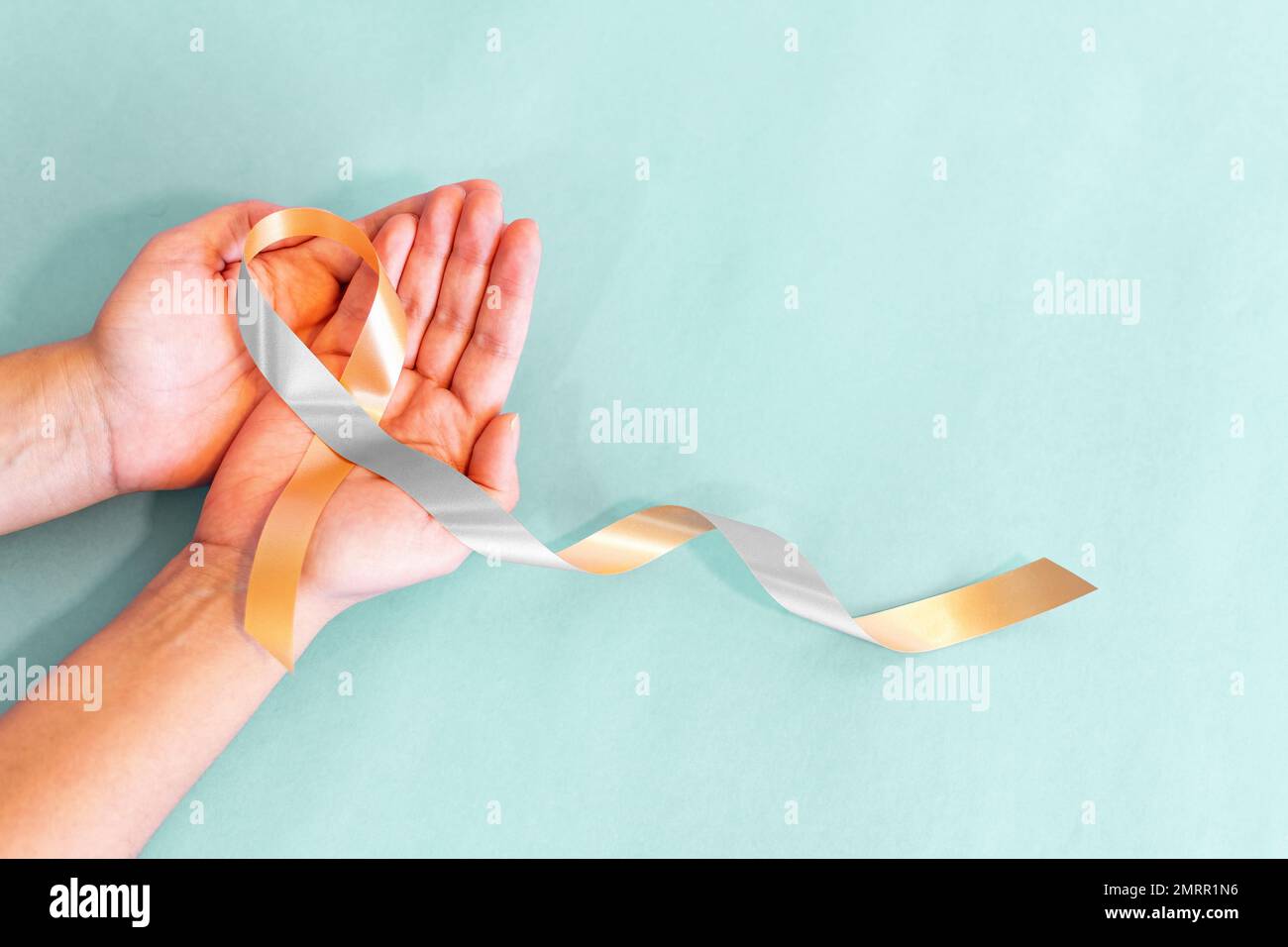 The gold and silver ribbon on helping hand for raising awareness on ...