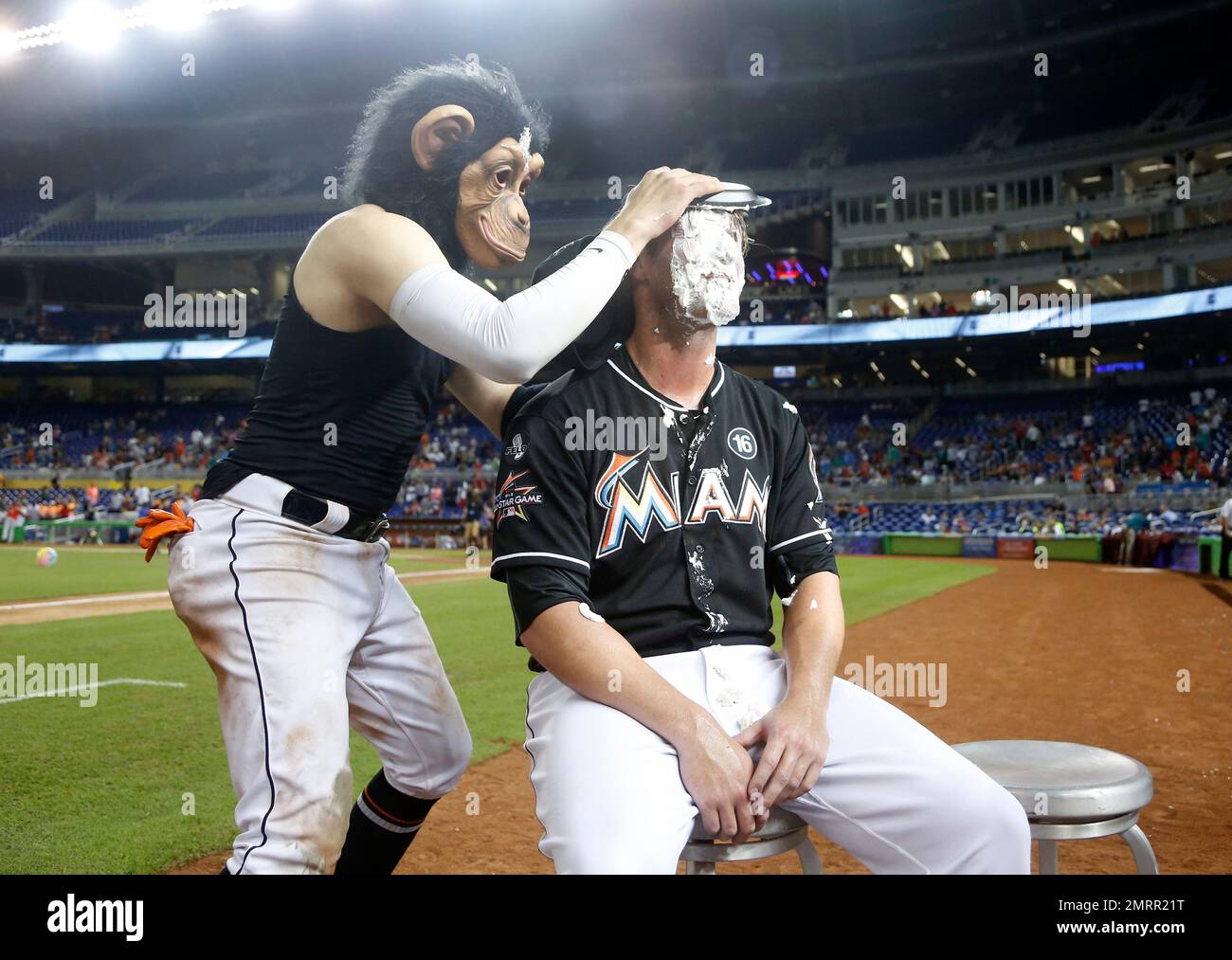 Wearing a monkey mask, Miami Marlins' Miguel Rojas, top, prepares to hit J.T.  Realmuto with a shaving cream pie as Realmuto does a postgame interview  after a baseball game against the Atlanta