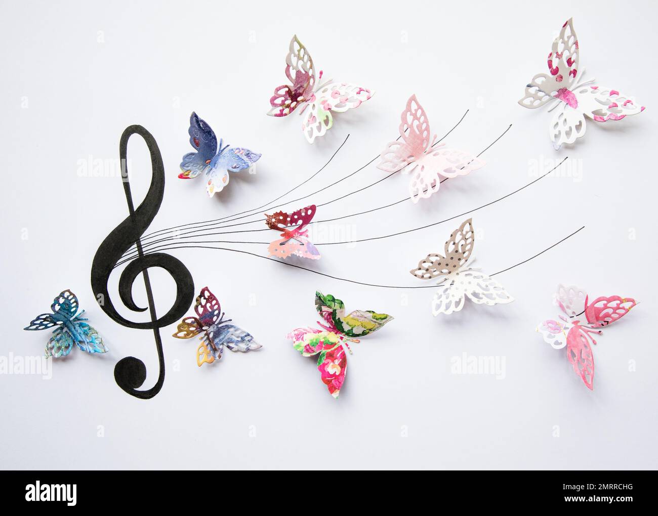 A closeup of colorful paper cut out butterflies eminating from an artistic musical staff Stock Photo