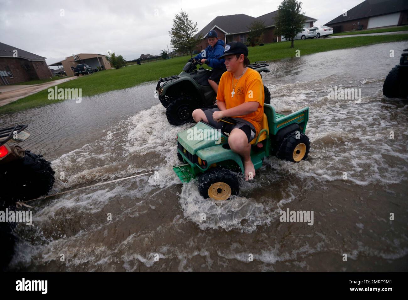 Kids pull a toy with an ATV in a street flooded by Tropical Storm