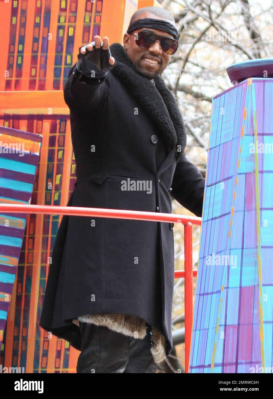 Clad in leather pants, headband, double-breasted wool coat and fingerless gloves rapper and fashion aficionado Kanye West waves to the crowd from a float during the 84th annual Macy's Thanksgiving Day Parade.  The parade, that started at 77th Street and Central Park West and travels south ending at 34th Street and 7th Avenue, featured its famed giant balloons including Kung Fu Panda, Sponge Bob Square Pants and Shrek, floats, performance groups and appearances by stars including Jessica Simpson, Kanye West and Kylie Minogue.  New York, NY. 11/25/10. Stock Photo