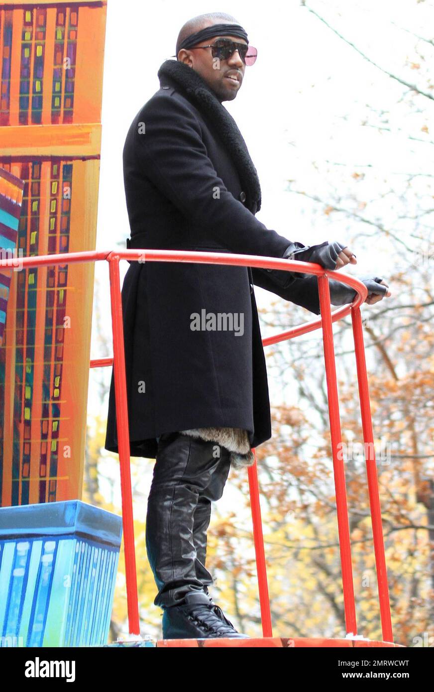 Clad in leather pants, headband, double-breasted wool coat and fingerless gloves rapper and fashion aficionado Kanye West waves to the crowd from a float during the 84th annual Macy's Thanksgiving Day Parade.  The parade, that started at 77th Street and Central Park West and travels south ending at 34th Street and 7th Avenue, featured its famed giant balloons including Kung Fu Panda, Sponge Bob Square Pants and Shrek, floats, performance groups and appearances by stars including Jessica Simpson, Kanye West and Kylie Minogue.  New York, NY. 11/25/10. Stock Photo