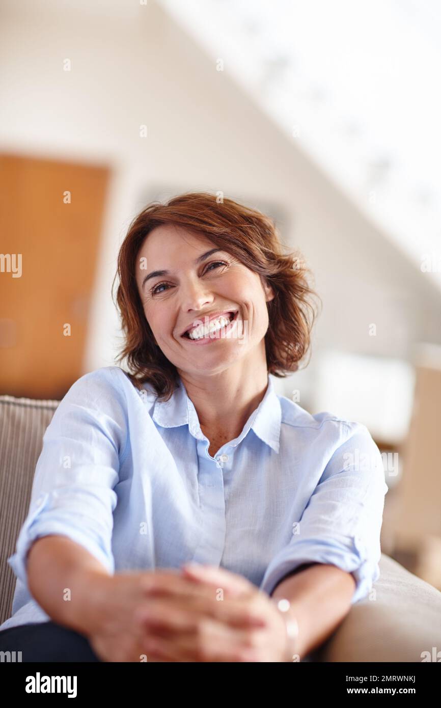 Happy days. a mature woman sitting on her sofa at home Stock Photo - Alamy