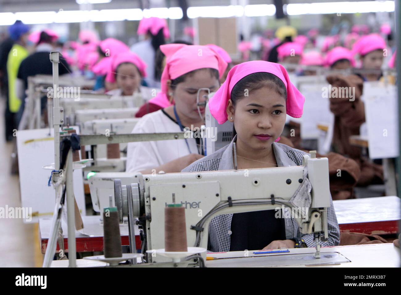 Cambodian garment workers operate sewing machine at a factory as they