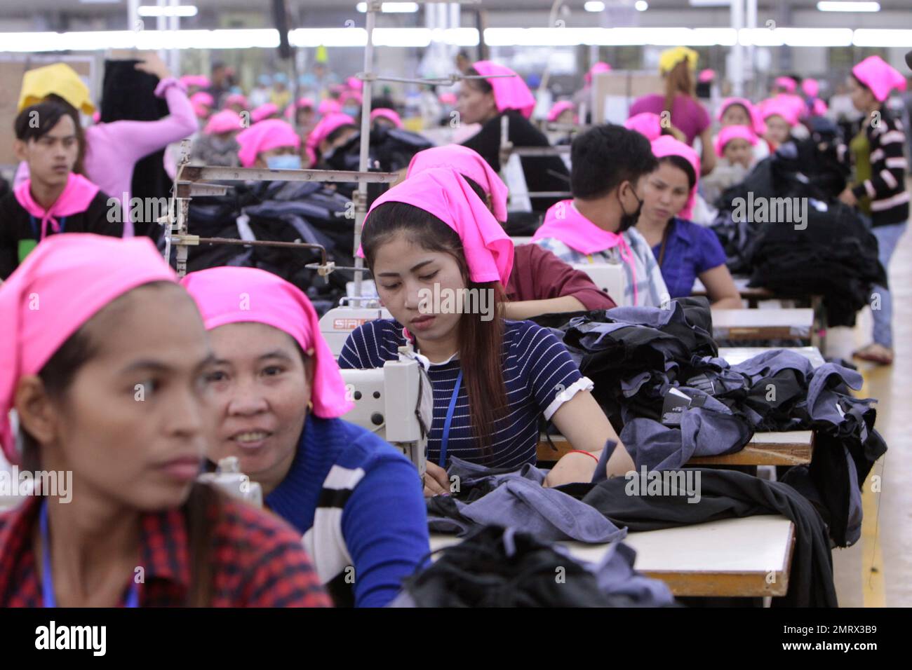 Cambodian garment workers operate a sewing machine at a factory as they
