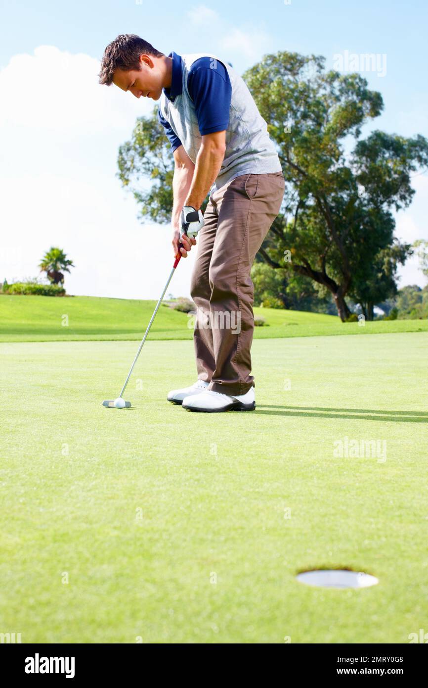 Golfer about to putt the ball. Full length of man playing golf and taking position to putt the ball in the hole. Stock Photo